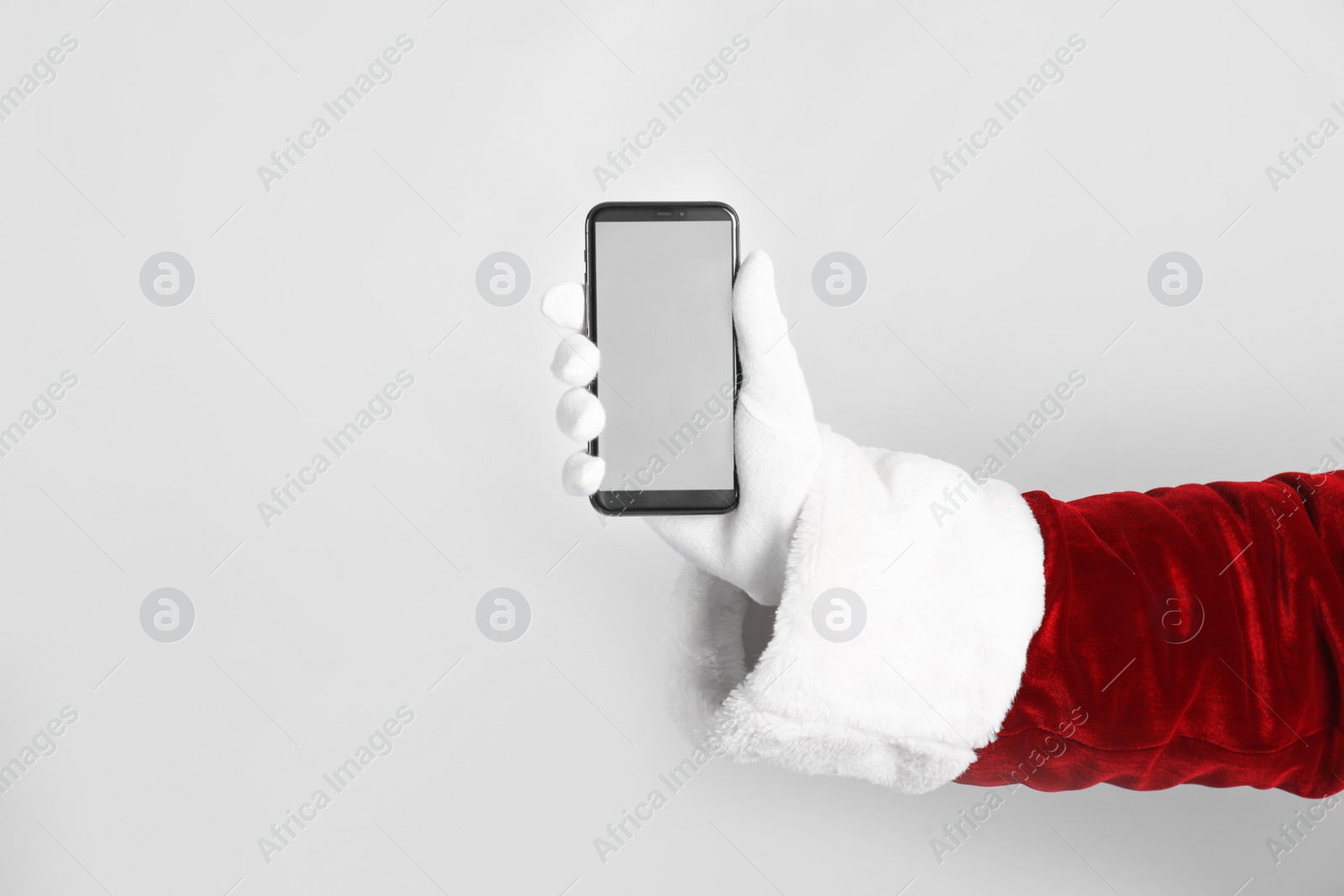 Photo of Santa holding modern mobile phone with blank screen on light grey background, closeup. Space for text