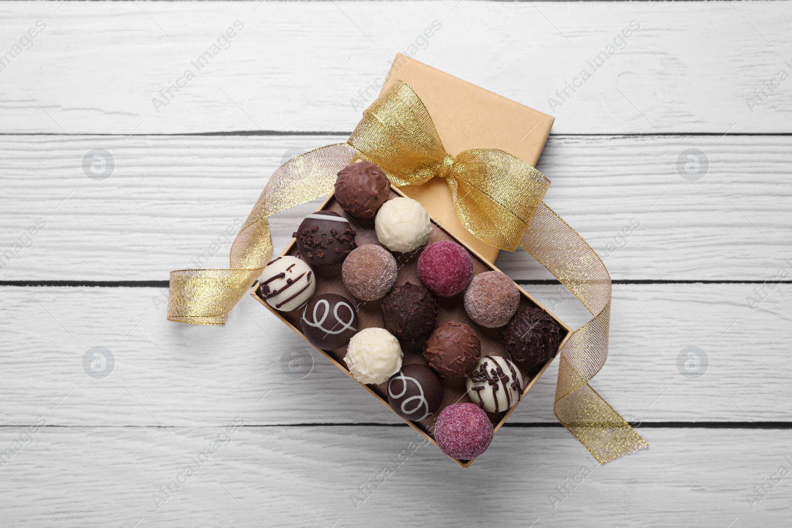 Open box with delicious chocolate candies on white wooden table, top view Photo of Open box with delicious chocolate candies on white wooden table, top view