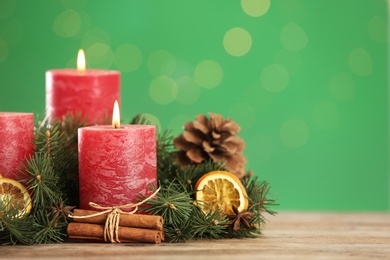 Beautiful Christmas composition with burning candles on table against green background. Space for text