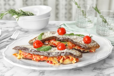 Photo of Baked eggplant with tomatoes, cheese and basil on marble table