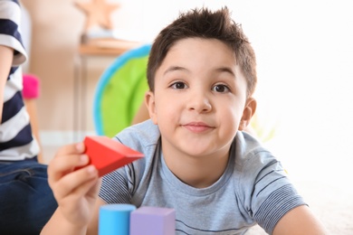 Photo of Cute little child playing with building blocks, closeup