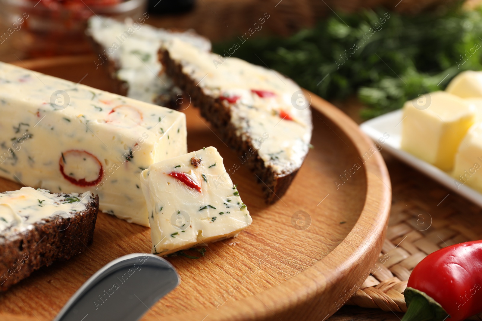 Photo of Tasty butter with dill, chili pepper and rye bread on table, closeup