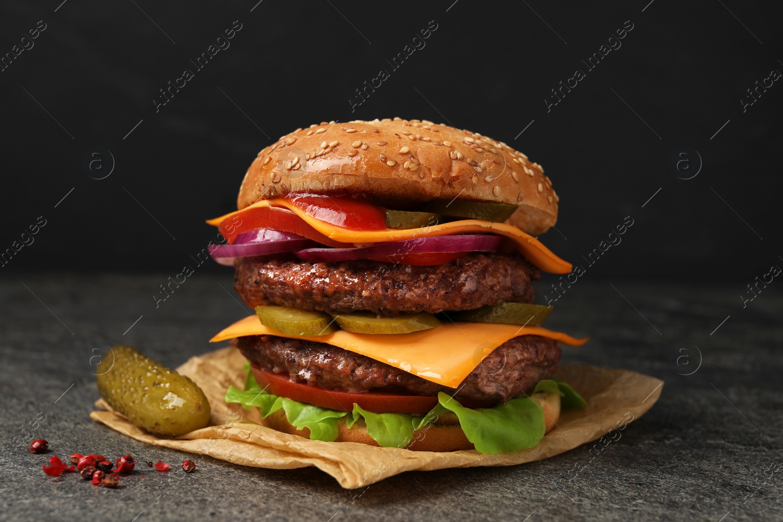 Photo of Delicious burger with meat cutlets, cheese, pickled cucumbers and lettuce on grey table, closeup