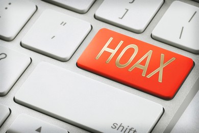 Red button with word Hoax on laptop keyboard, closeup