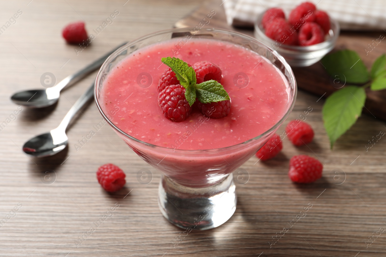 Photo of Delicious raspberry mousse with mint on wooden table