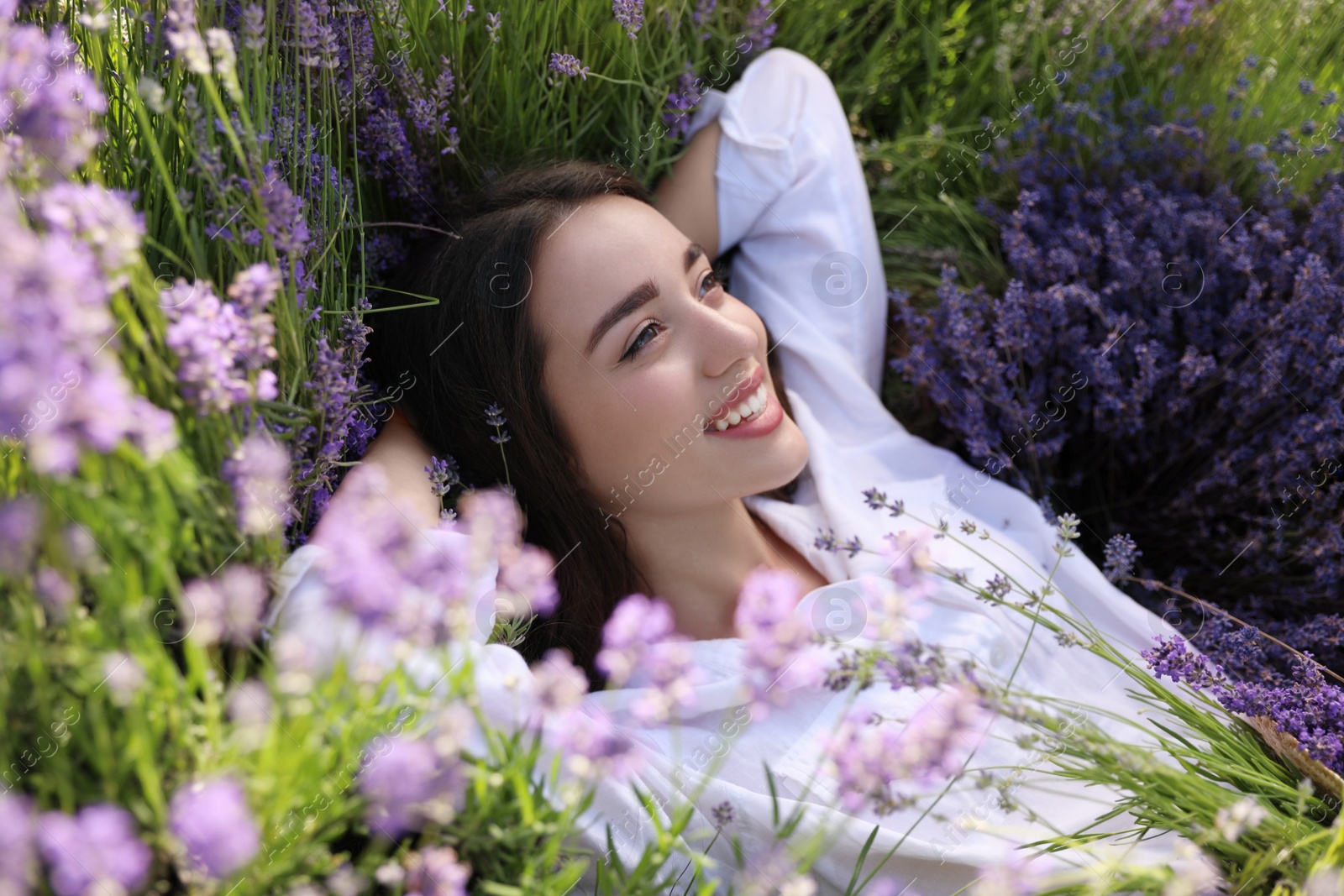 Photo of Young woman lying in lavender field on summer day