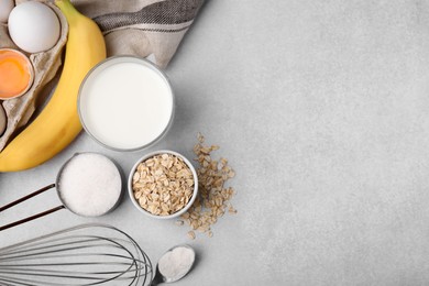 Photo of Different ingredients for cooking tasty oatmeal pancakes on grey table, flat lay. Space for text