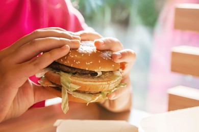 Photo of WARSAW, POLAND - SEPTEMBER 16, 2022: Woman with McDonald's burger at table in cafe, closeup