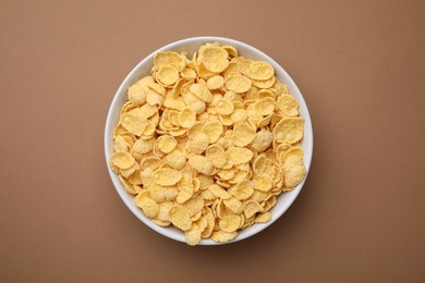 Photo of Breakfast cereal. Tasty corn flakes in bowl on brown table, top view