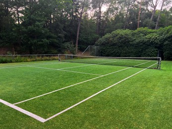 Photo of Tennis court with green grass and net outdoors