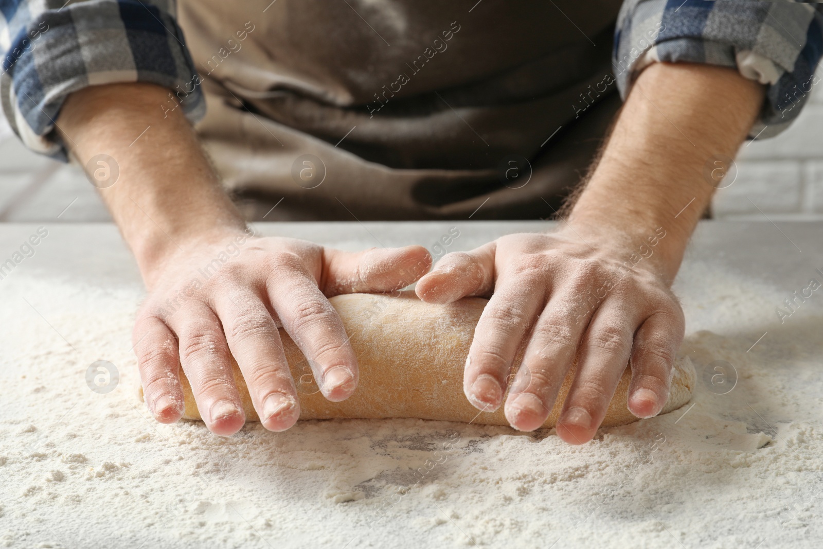 Photo of Young man kneading dough for pasta on table