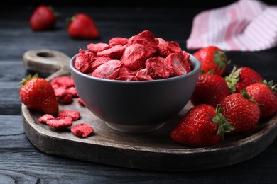 Photo of Freeze dried and fresh strawberries on black wooden table, closeup