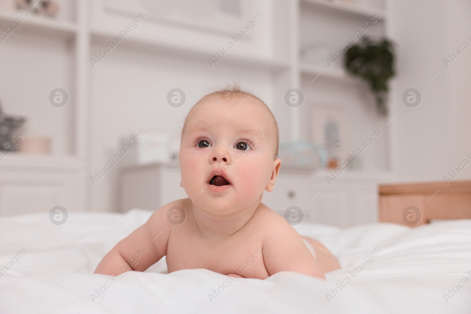 Photo of Cute baby lying on white bed at home