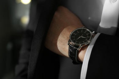 Photo of Businessman with luxury wrist watch on blurred background, closeup