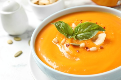 Photo of Delicious pumpkin soup in bowl on table, closeup