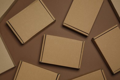 Photo of Many closed cardboard boxes on brown background, flat lay