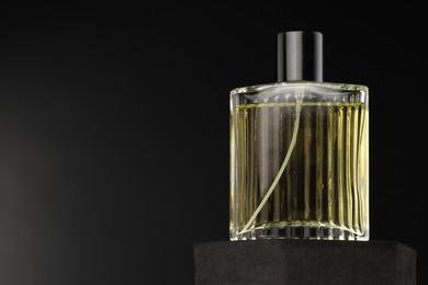 Photo of Luxury men`s perfume in bottle against dark background, space for text