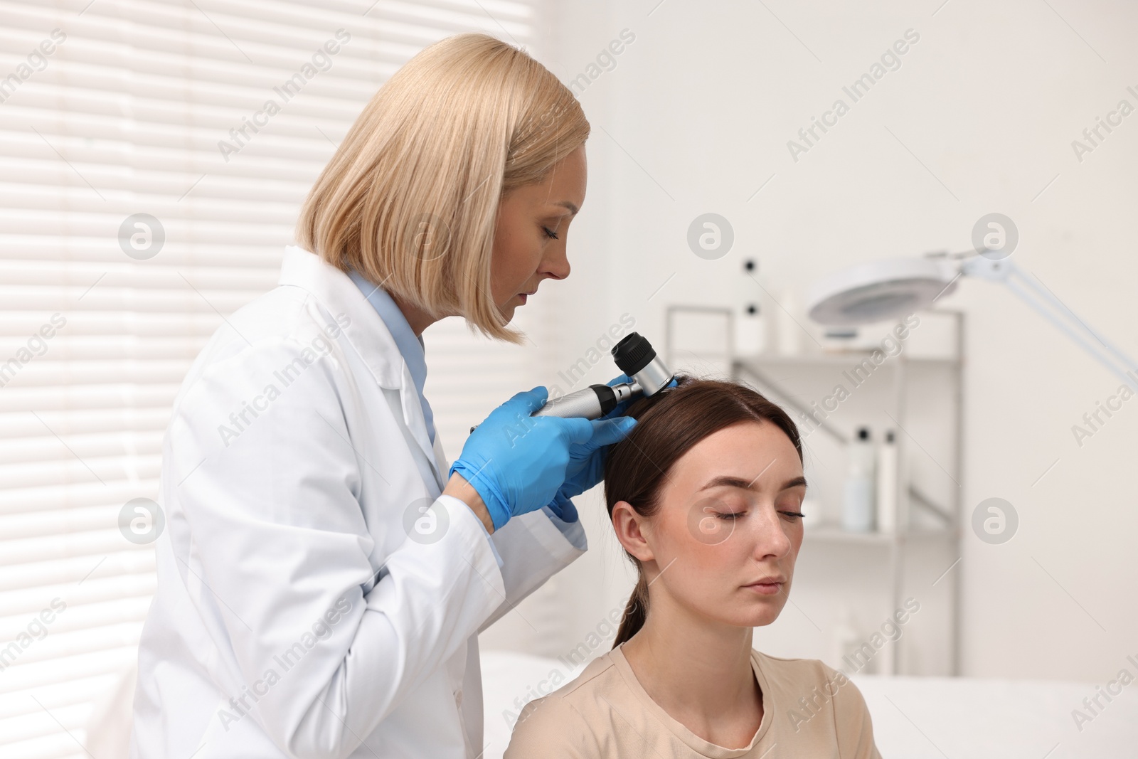 Photo of Trichologist with dermatoscope examining patient`s hair in clinic