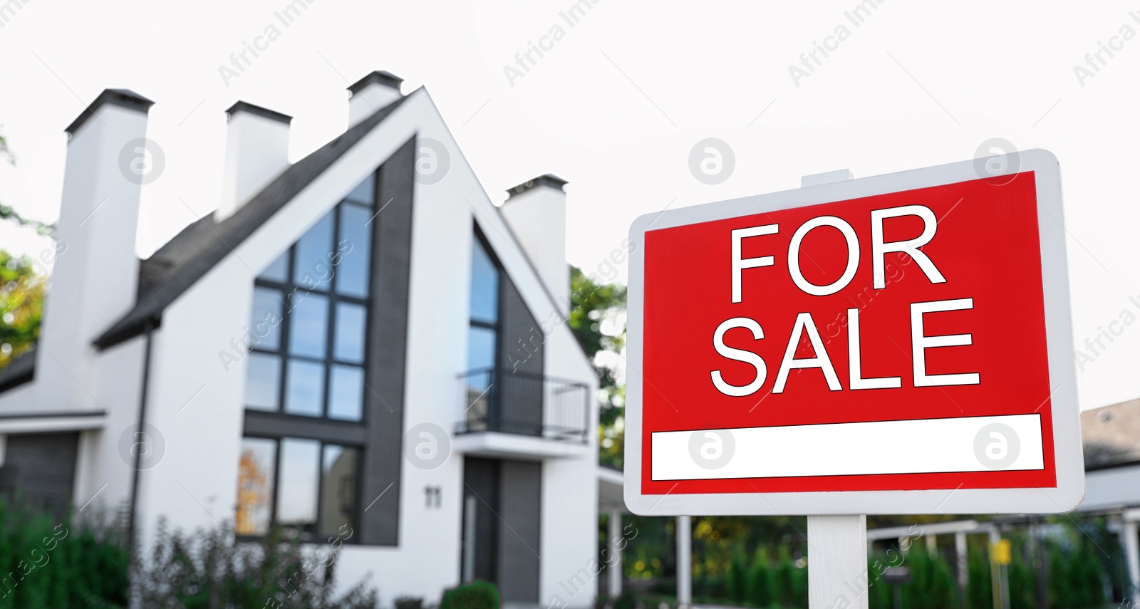 Photo of Red real estate sign near house outdoors on sunny day