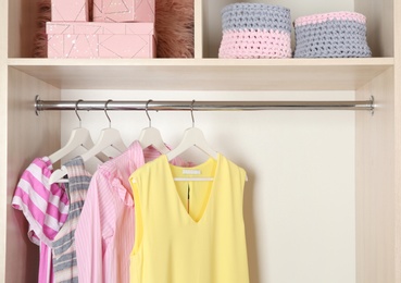 Photo of Stylish girl's clothes hanging in wardrobe, closeup