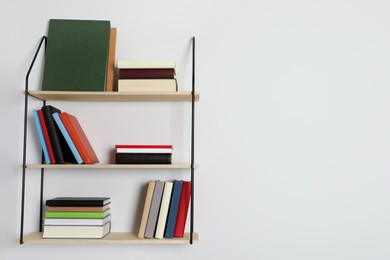 Shelves with many hardcover books on white wall. Space for text