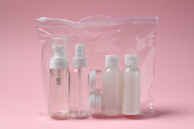 Cosmetic travel kit in plastic bag on pink background. Bath accessories