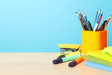 Photo of Composition with different school stationery on wooden table against light blue background, space for text. Back to school