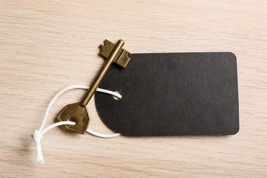 Key with blank tag on wooden table, top view. Keyword concept