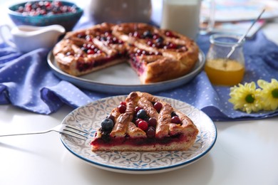 Photo of Piece of delicious currant pie with fresh berries served on white table