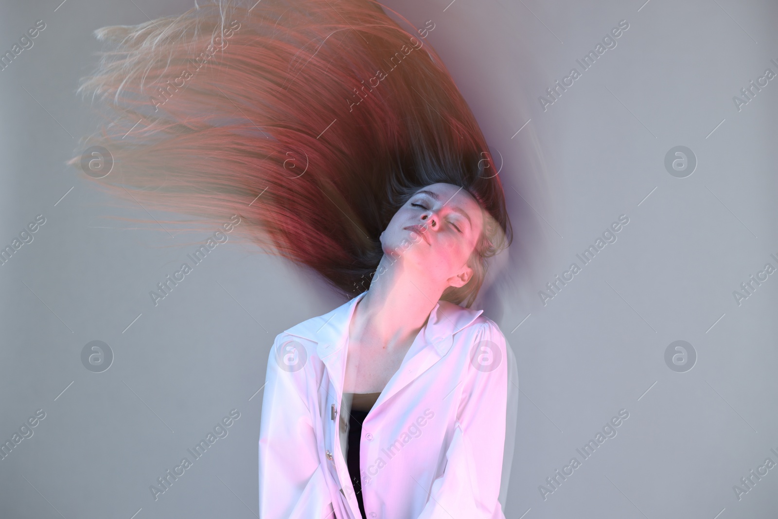 Photo of Fashionable portrait of beautiful young woman on grey background, long-exposure photography