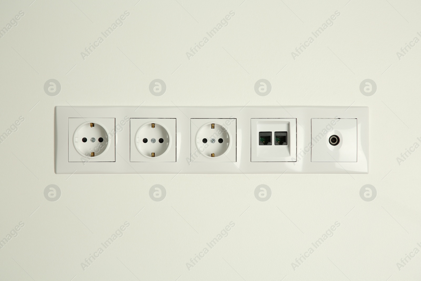 Photo of Many power sockets with ethernet and TV coax plates on white wall indoors