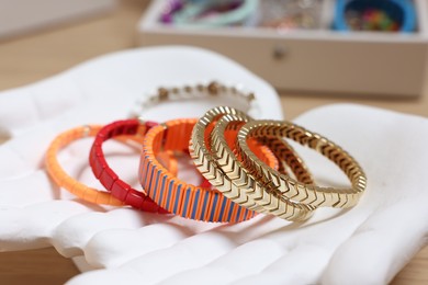 Photo of Ceramic hand stand with many different bracelets on table, closeup