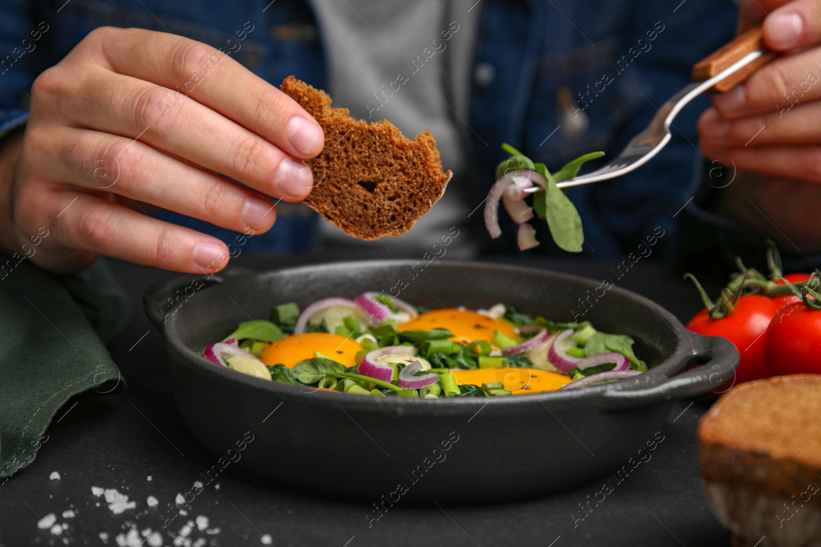 Photo of Woman eating tasty Shakshuka at table, closeup