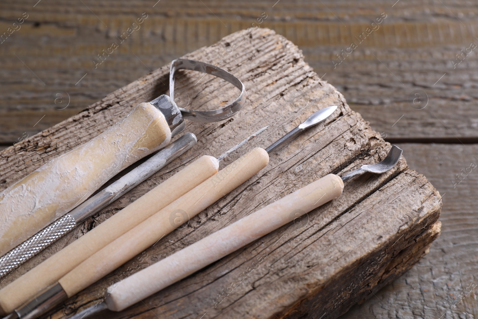 Photo of Set of different clay crafting tools on wooden table, closeup