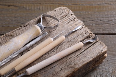 Set of different clay crafting tools on wooden table, closeup