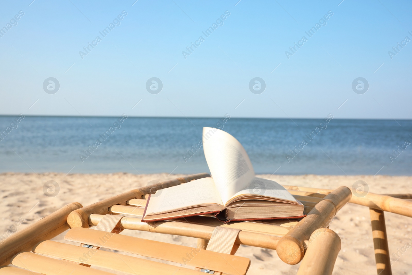 Photo of Book on wooden deck chair at seaside. Reading while vacation