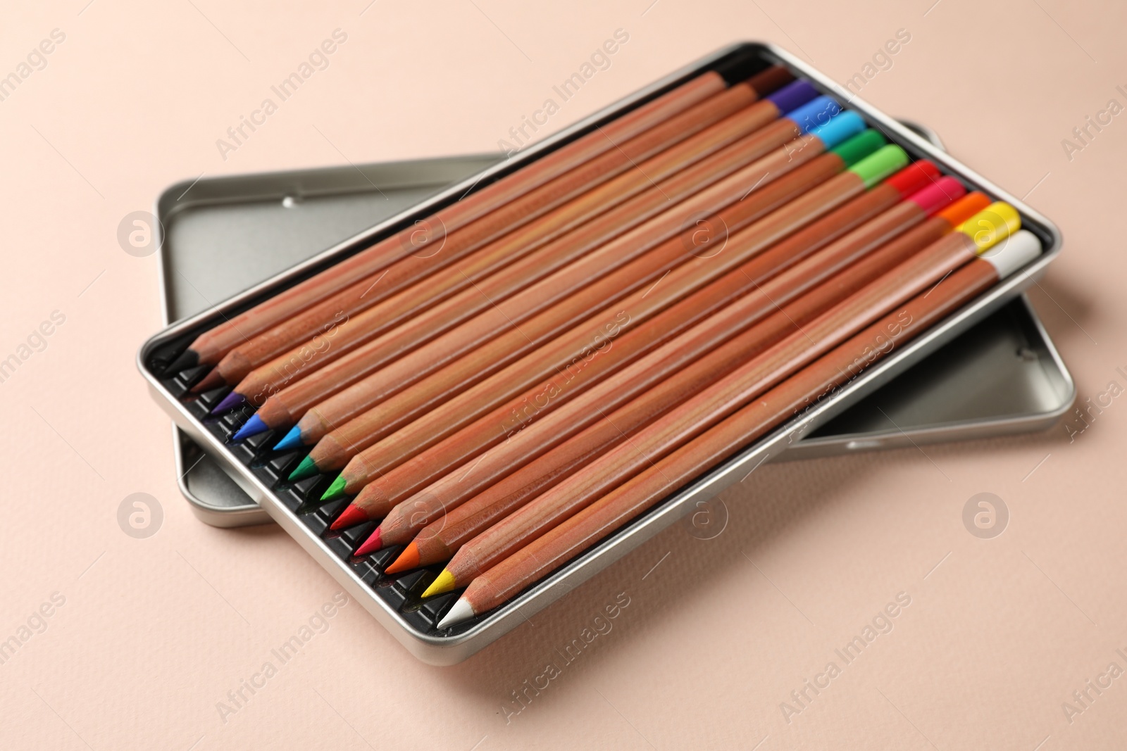 Photo of Box with many colorful pastel pencils on beige background. Drawing supplies