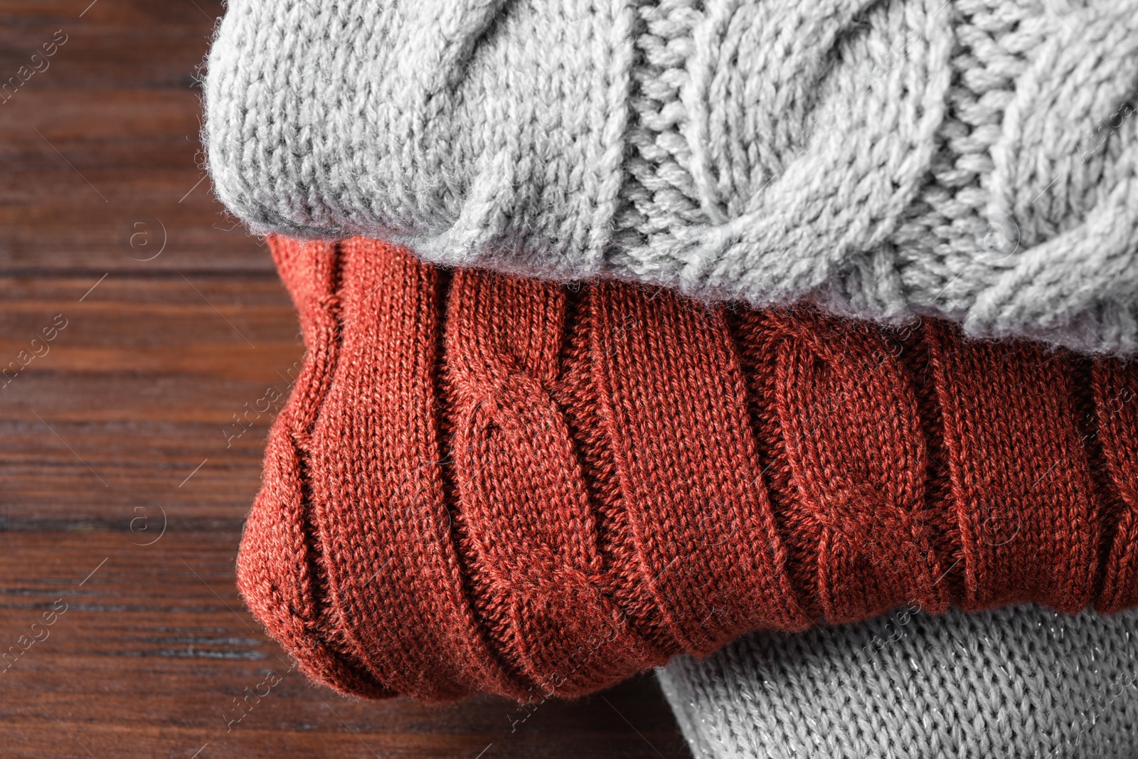 Image of Stack of folded warm sweaters on wooden background, closeup