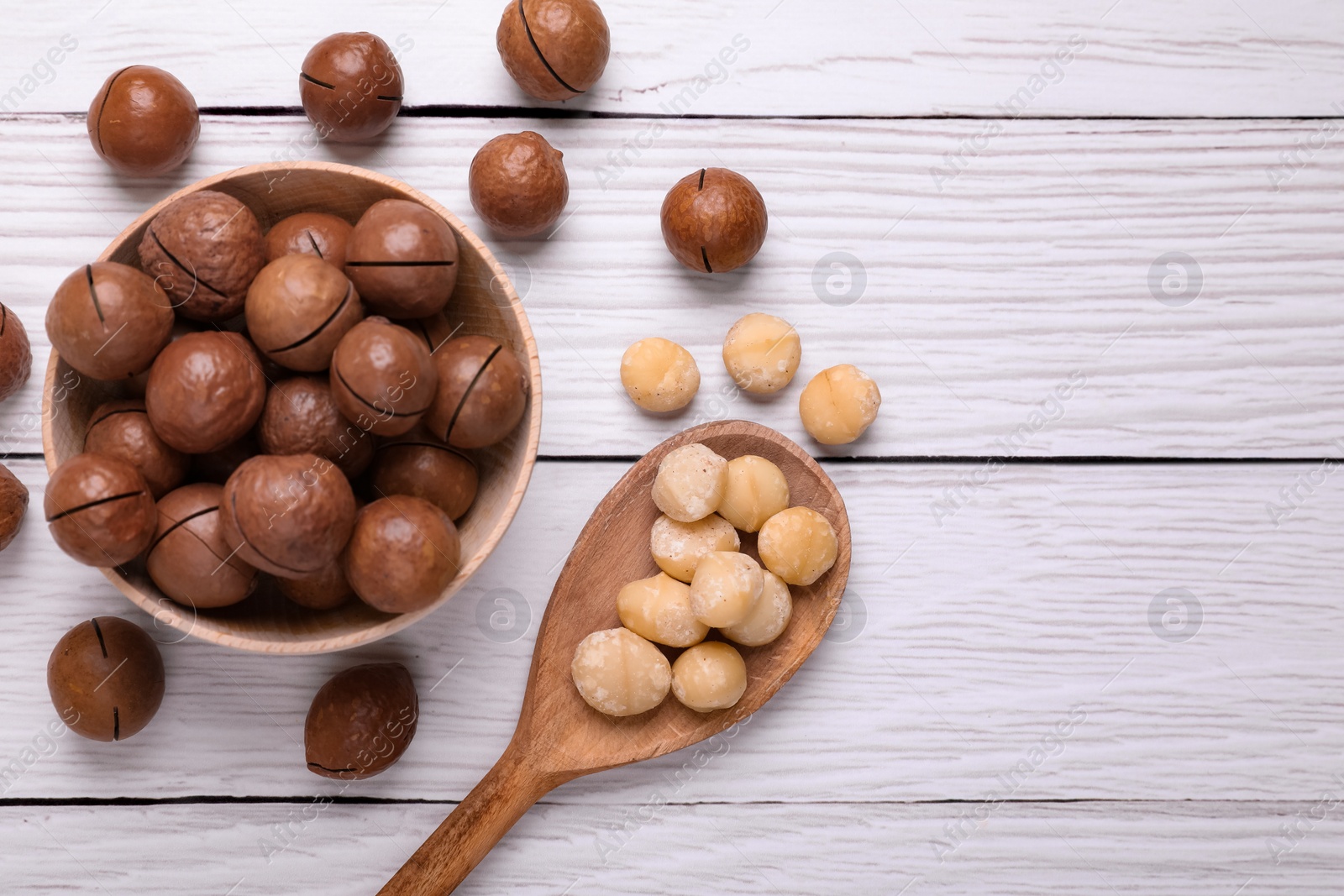 Photo of Delicious organic Macadamia nuts on white wooden table, flat lay. Space for text