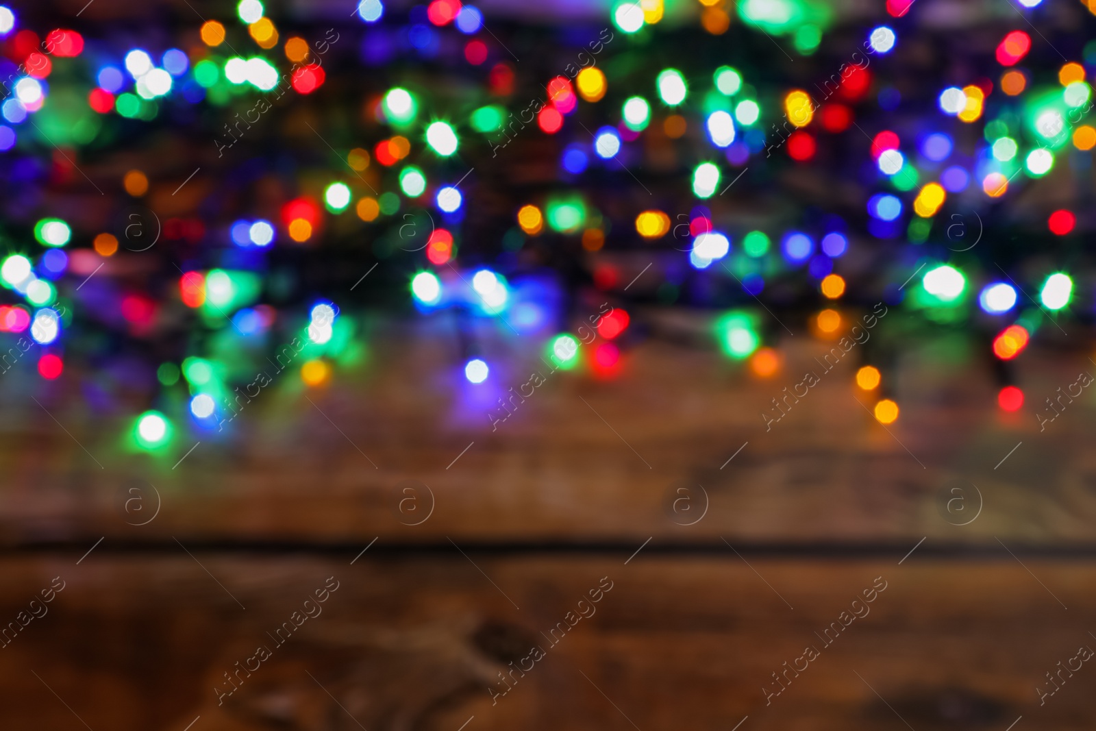 Photo of Glowing festive lights on wooden table, top view with space for text. Bokeh effect