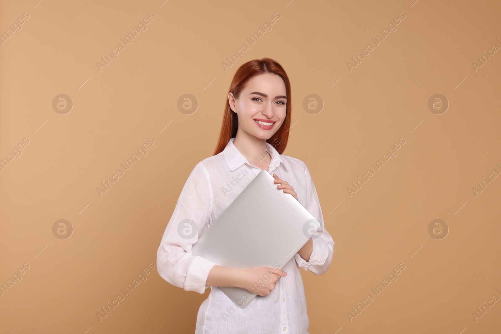 Photo of Smiling young woman with laptop on beige background