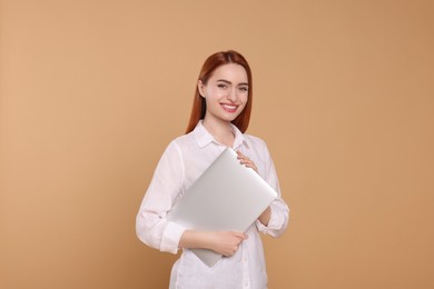 Photo of Smiling young woman with laptop on beige background