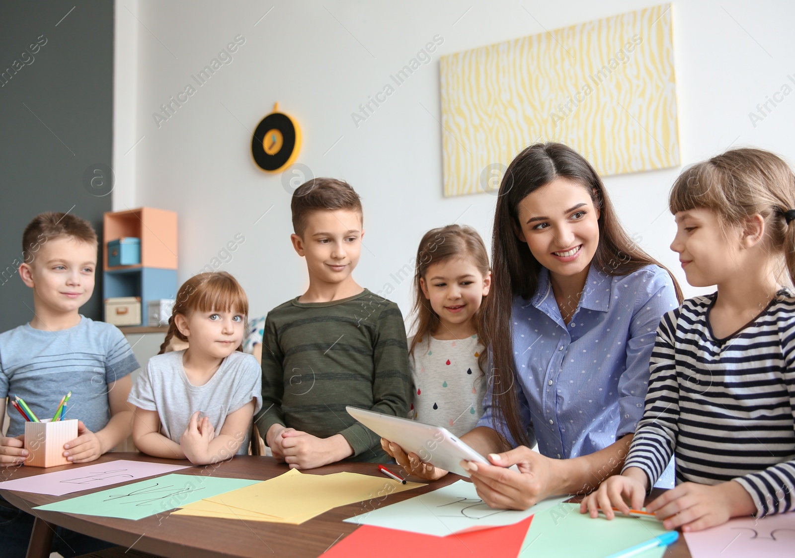 Photo of Cute little children with teacher in classroom at school