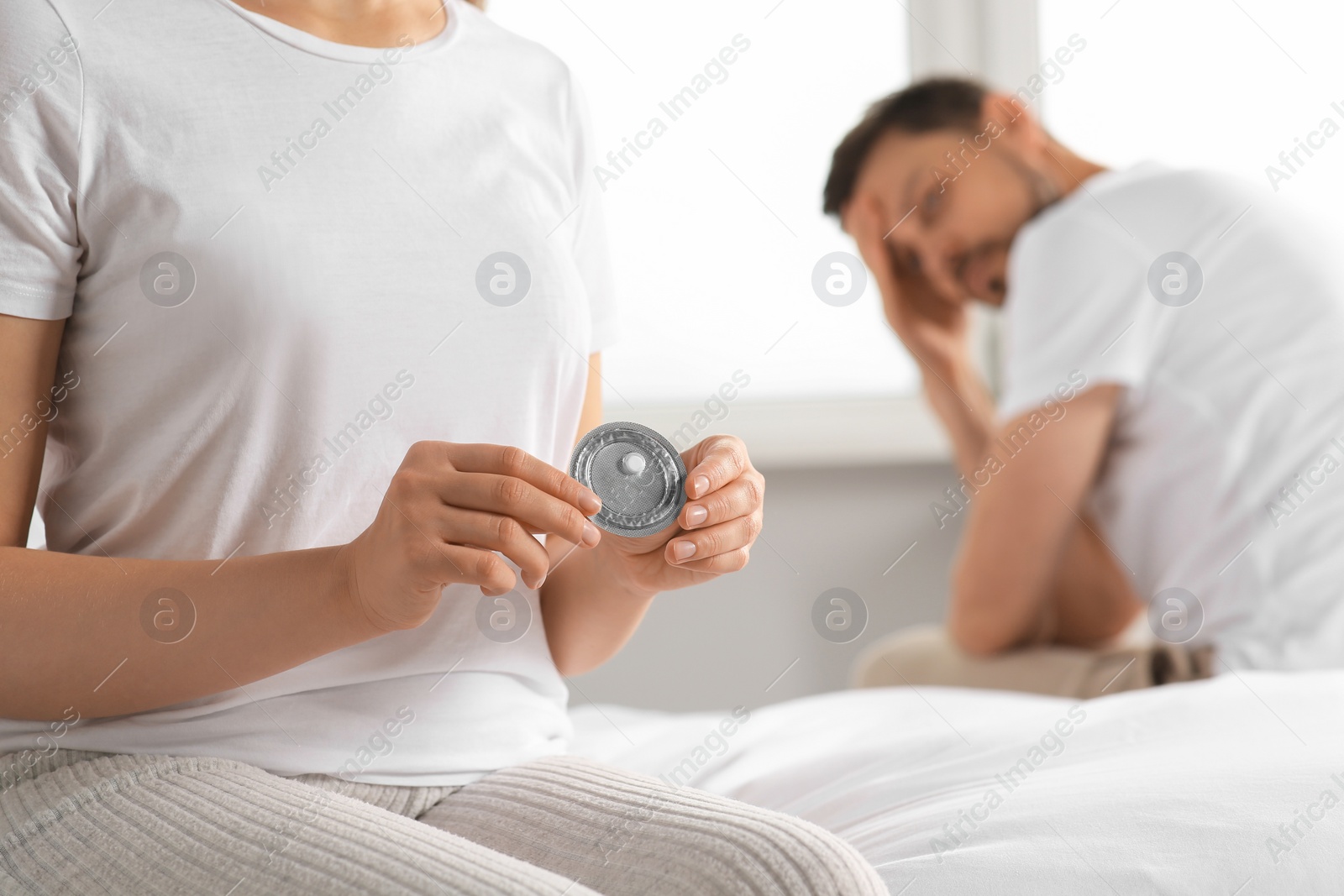 Photo of Couple in bedroom. Woman with blister of emergency contraception pill, closeup