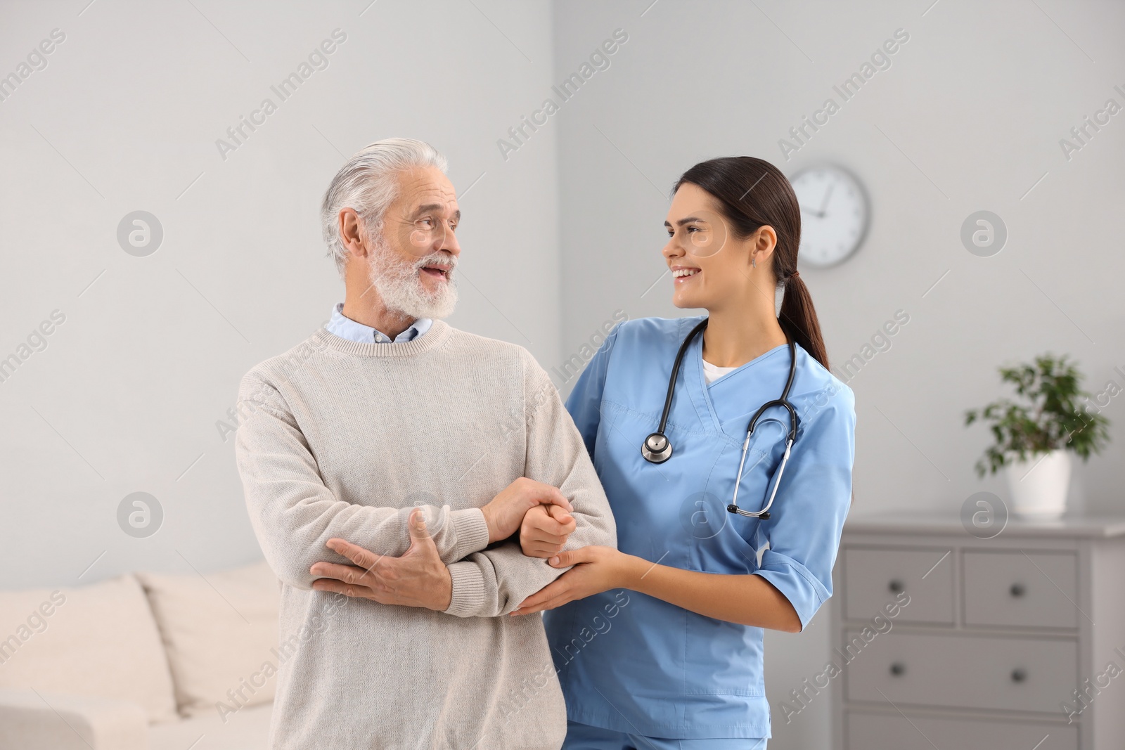 Photo of Smiling nurse supporting elderly patient in hospital