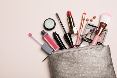 Photo of Cosmetic bag with makeup products and accessories on beige background, flat lay