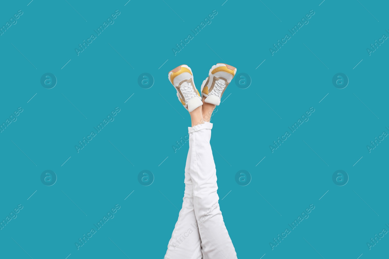 Photo of Woman in stylish sport shoes on light blue background