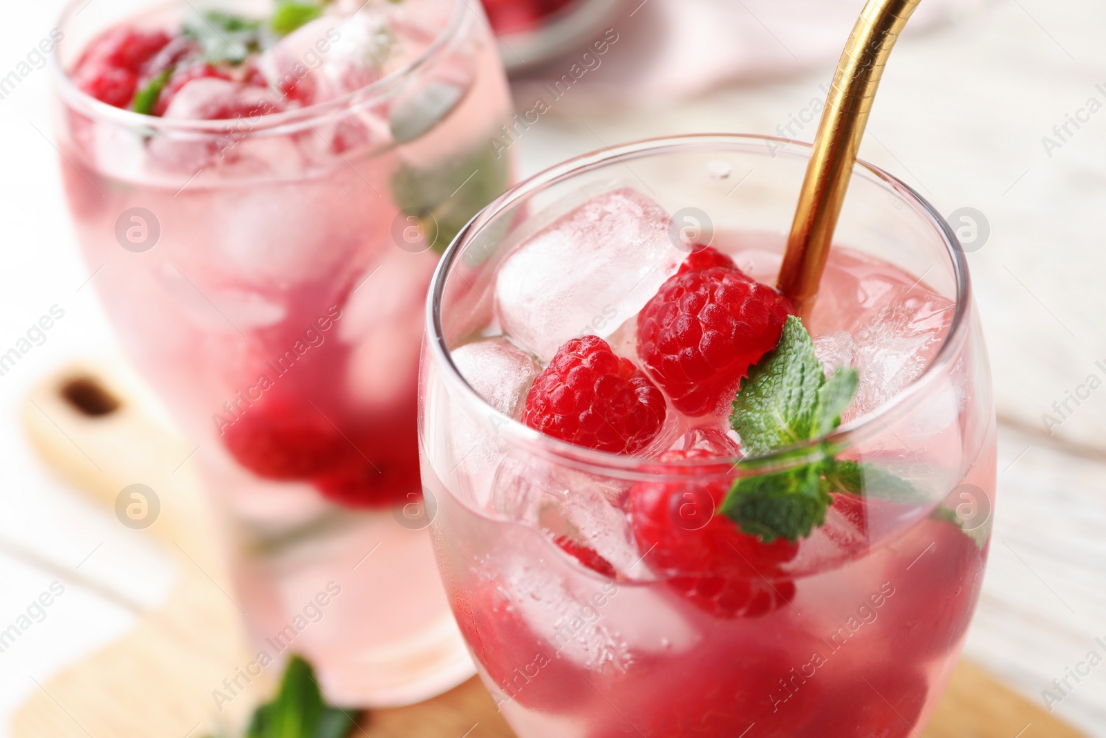 Photo of Glass of refreshing drink with raspberry and mint on table, closeup view. Space for text