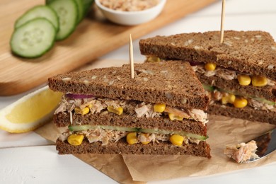 Photo of Delicious sandwiches with tuna and vegetables on white wooden table
