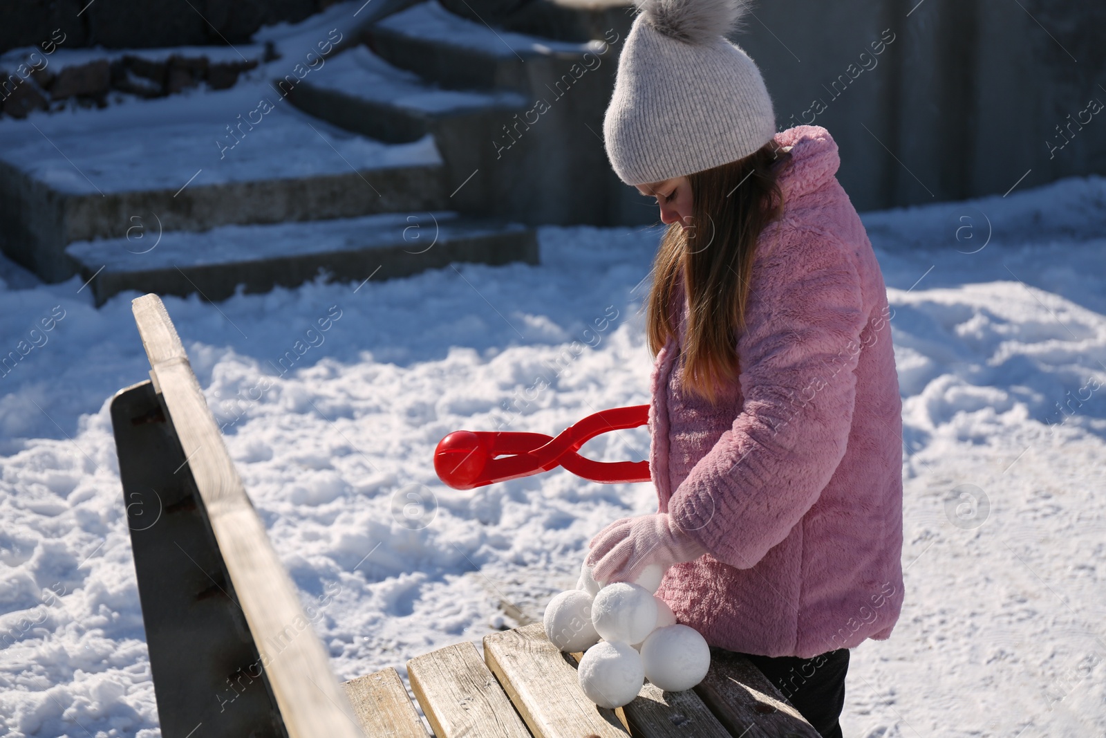 Photo of Cute little girl playing with snowball maker outdoors